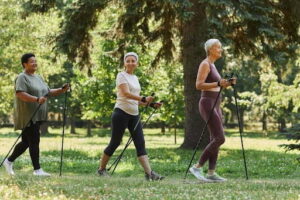 Side view portrait of senior women walking with poles in green park